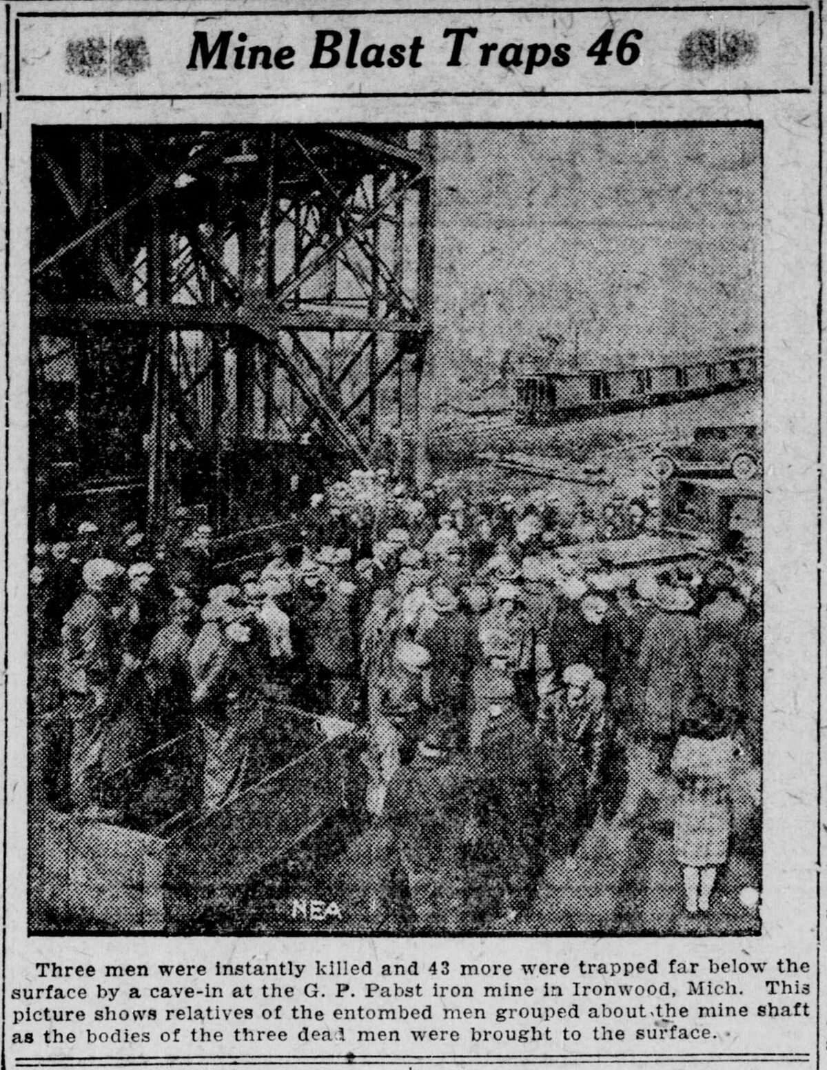 Newspaper clipping headed “Mine Blast Traps 46”: a halftone photograph of a crowd at the foot of a mine headframe, credited NEA, above a caption about relatives waiting as the bodies of three men were brought up.